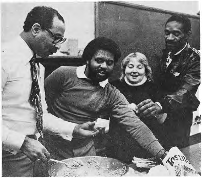 People preparing food in the photograph accompanying the community-school cooking article.