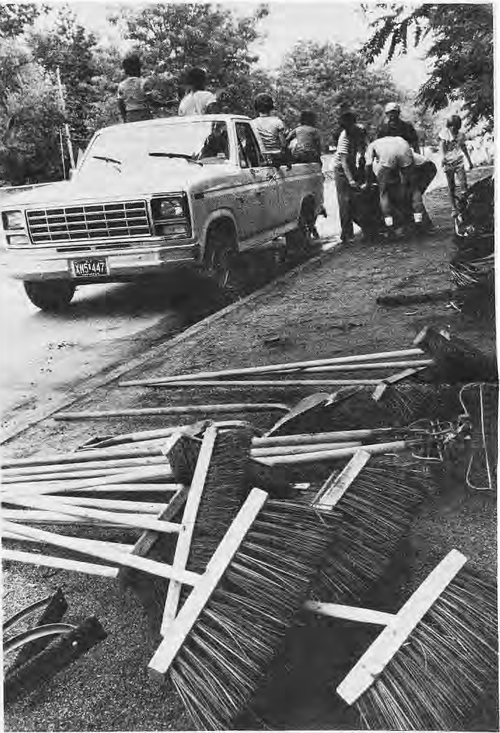 Neighbors collecting discarded wood and debris beside a pickup truck.