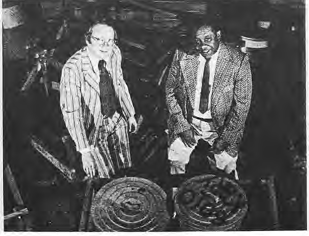 Two participants beside covered dishes at a historical gathering.