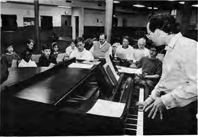 Tom Clear at the piano with community theater performers.