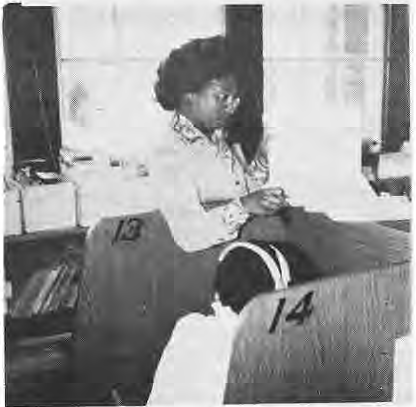 Mrs. Ware beside numbered listening booths at Hamilton School.