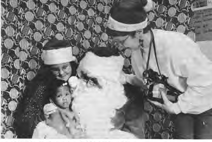 Alicia and Erica Webb assist Santa at SDCC Christmas Party. Photographer not credited.