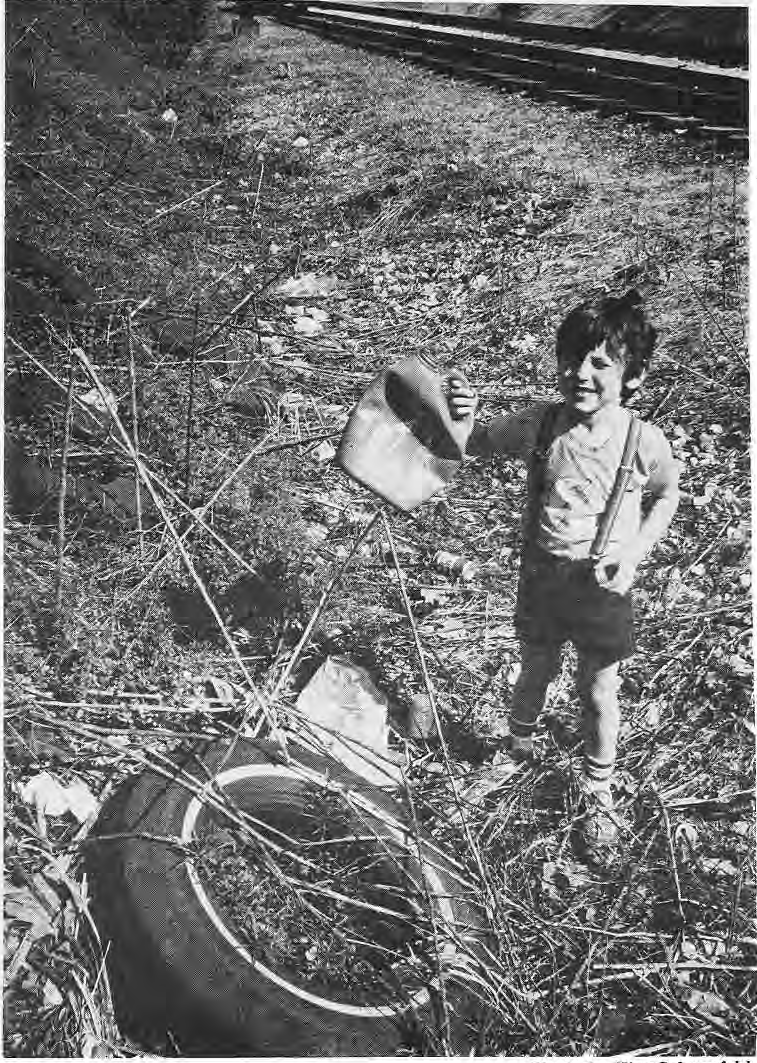 A young volunteer carrying a discarded container beside railroad tracks during Operation BLITZ.