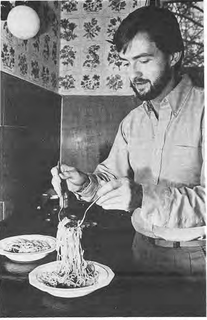 Dwight Matthews tossing spaghetti in his kitchen.