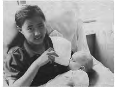 Crossroads student Wei Wei Shannon feeds a baby at Stella Maria Day Care Center as part of school-wide community service. Photographer not credited.
