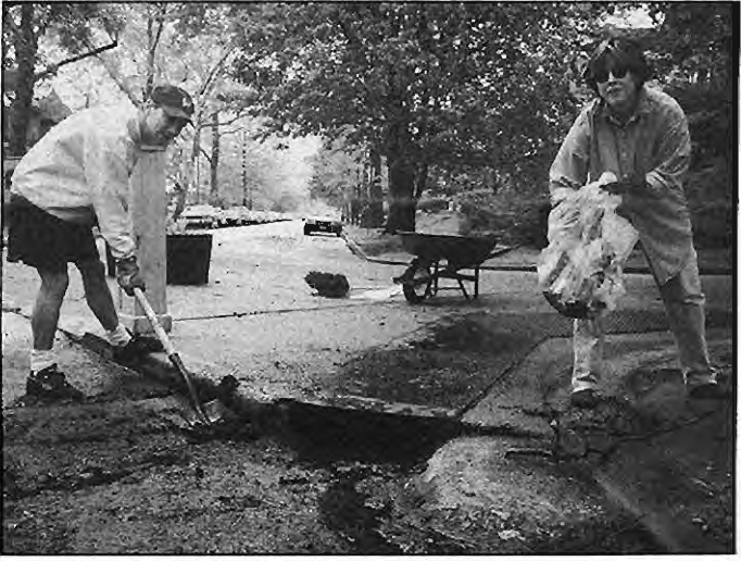 Mark Banaszak,block captain of6000Westminster,and Becky Homan unclog the storm drain on Rosedale. Photo by King Schoenfeld.