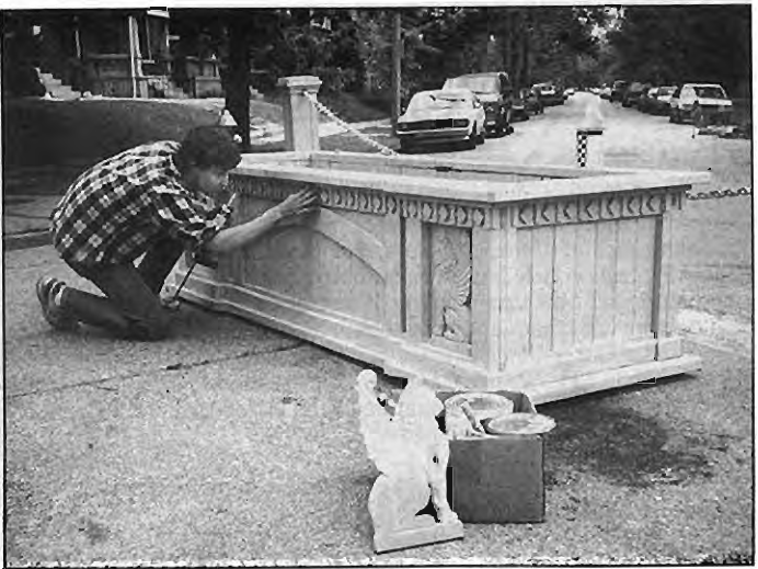 Andy Cross puts caulk into his first planter for neighborhood traffic barricades. Photographer not credited.