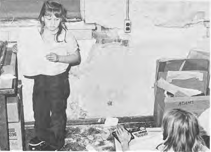 Children in an interior with damaged wall surfaces; source does not identify the school.