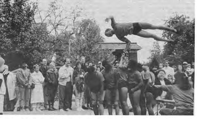 Several hundred residents and visitors attended Art Exposed ’90 on October 21. One of the crowd pleasers was the Circus Flora acrobatic troop, shown here as one performer makes a flying leap over the other five, picking up a hat along the way.