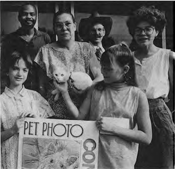 Christine Smith, center right of husband Bruce in cowboy hat, at Pet Photo Contest at old library kiosk. Photographer not credited.
