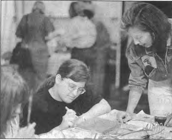 Among the dozens creating tiles for the MetroLink parking lot on September28were(from left)Emily Yonker and Alicia Webb,as Nancy DeBettencourt looks on. Photographer not credited.