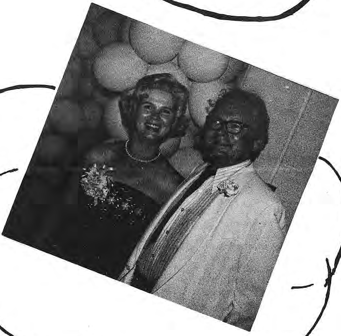 A couple photographed beneath prom decorations.