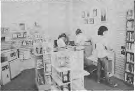 Library interior, librarian and patrons. Original source caption describes librarian Charles Lamkin and patrons but position label is inconsistent. Photographer not credited.