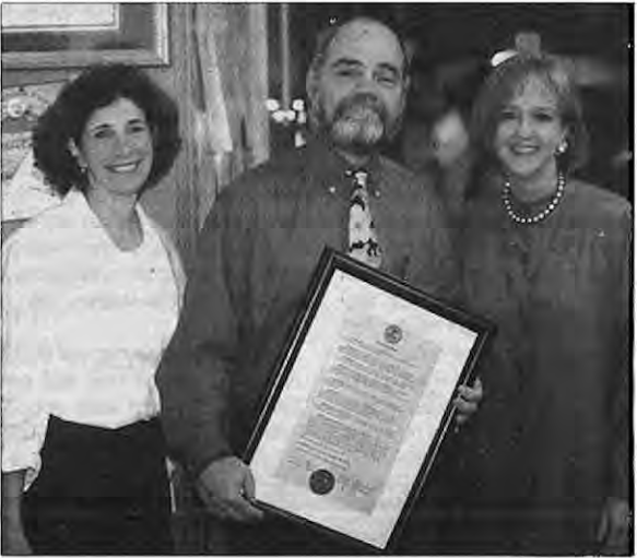 Tom receives City Proclamation from Lyda Krewson, with Board president Sue Schlichter on left. Photographer not credited.
