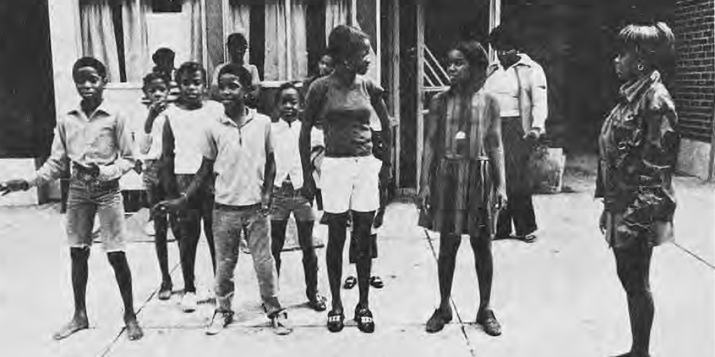 Neighborhood children and leader Robin Edwards outside the Krib, identified in the original caption.