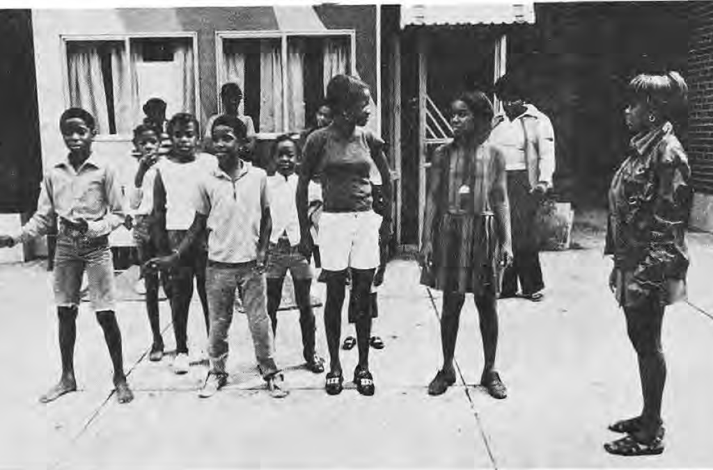 Neighborhood children and leader Robin Edwards outside the Krib, identified in the original caption.