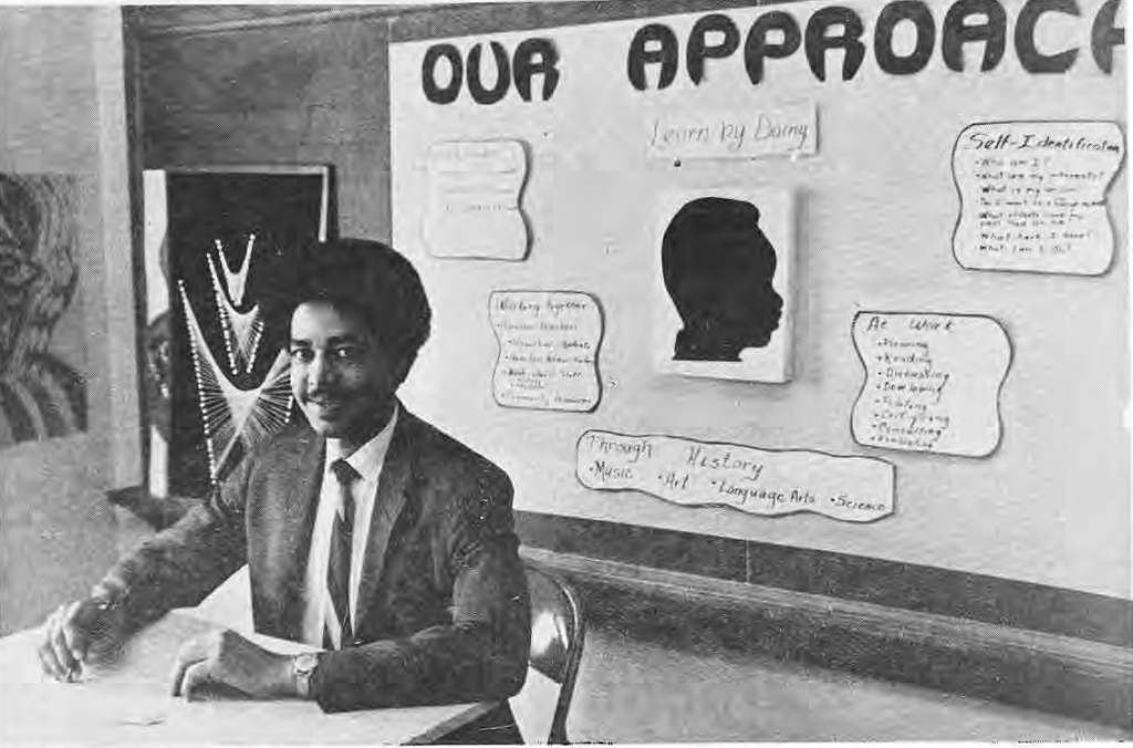 Shellie Jordan seated at a table in front of an “Our Approach” teaching display.