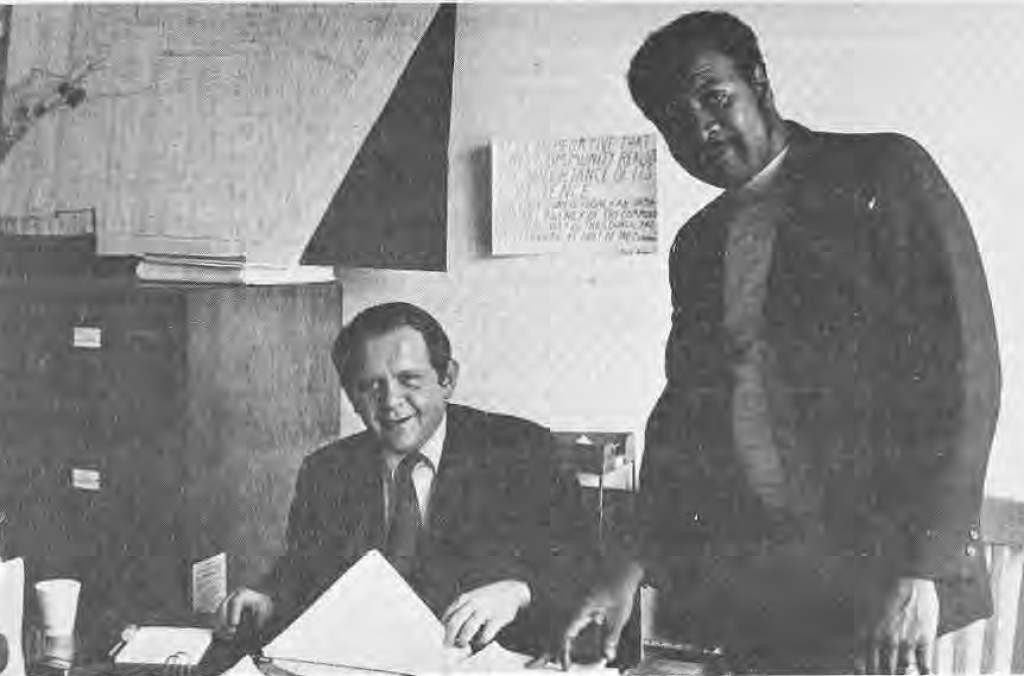 Bob Moore seated at a desk beside Calvin Stuart in the Community Council office.