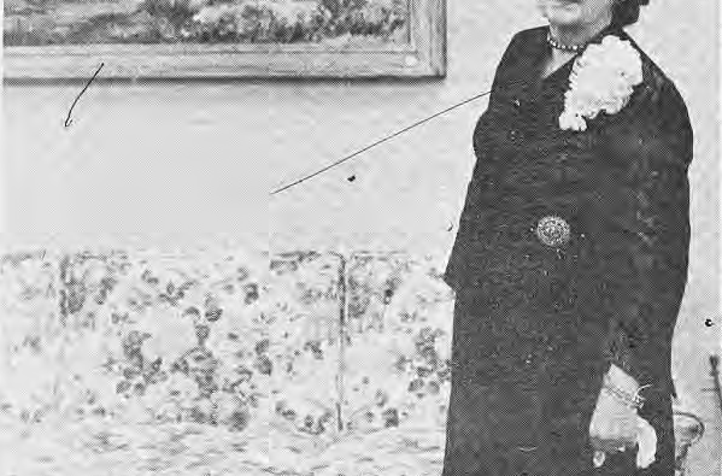 Olive Chaffee standing beside a painting at her exhibit.