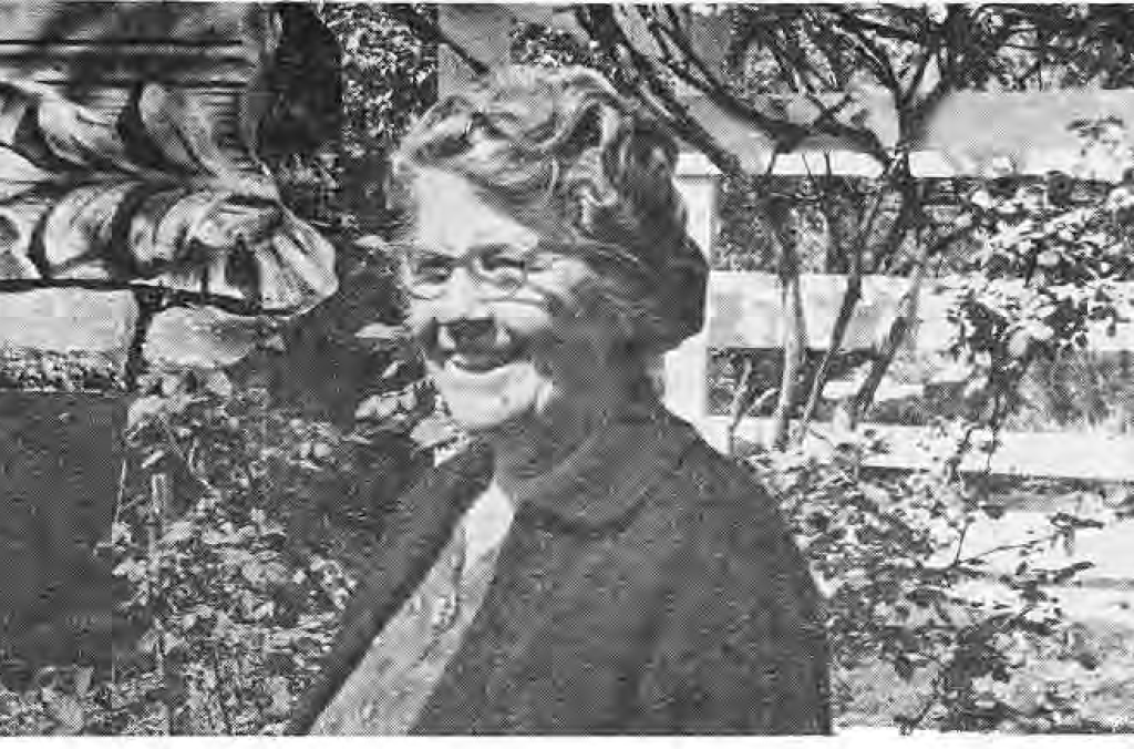Mrs. Keiffer in her garden beside a hybrid tea rose and stone ornament, as identified in the original caption.